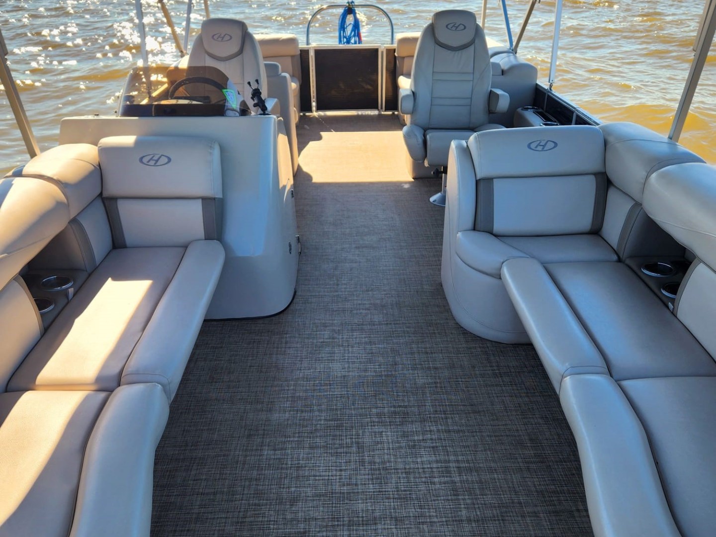 Interior view of a pontoon boat with cushioned seating on a sunny day.