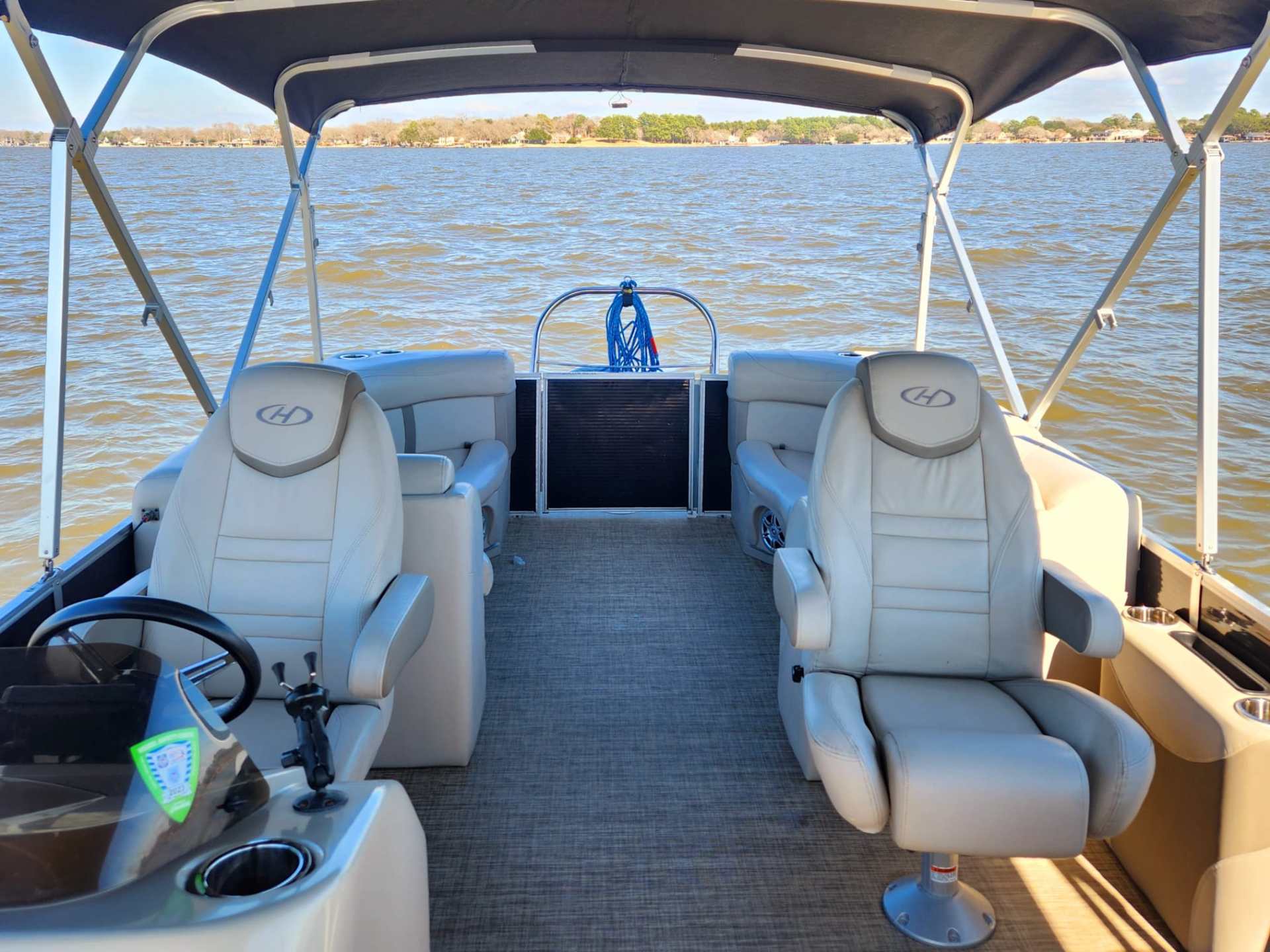 Pontoon boat interior with two captain chairs on a sunny day.