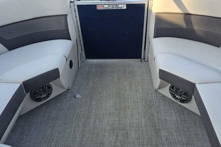 Pontoon boat interior with seating, carpeted floor, and view of water.