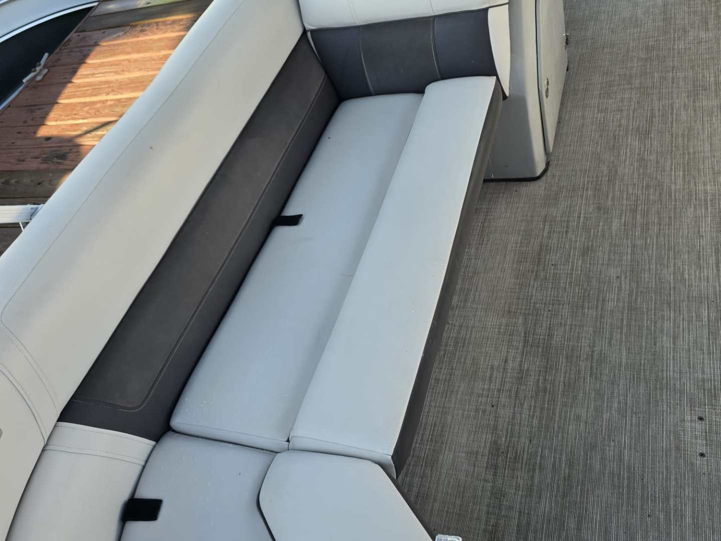 Empty boat seats with gray and white cushions on a docked boat.