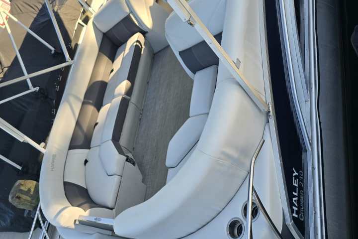 Interior of a pontoon boat with cushioned seating and a canopy.