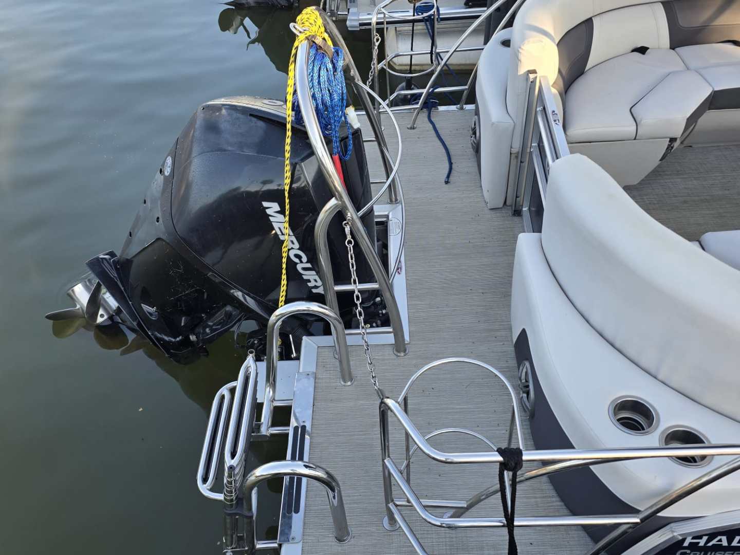 Pontoon boat with Mercury motor docked on calm water