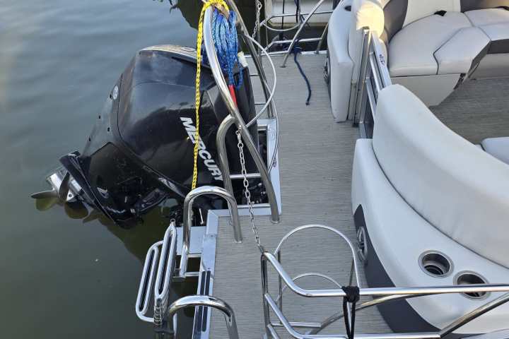 Pontoon boat with Mercury motor docked on calm water