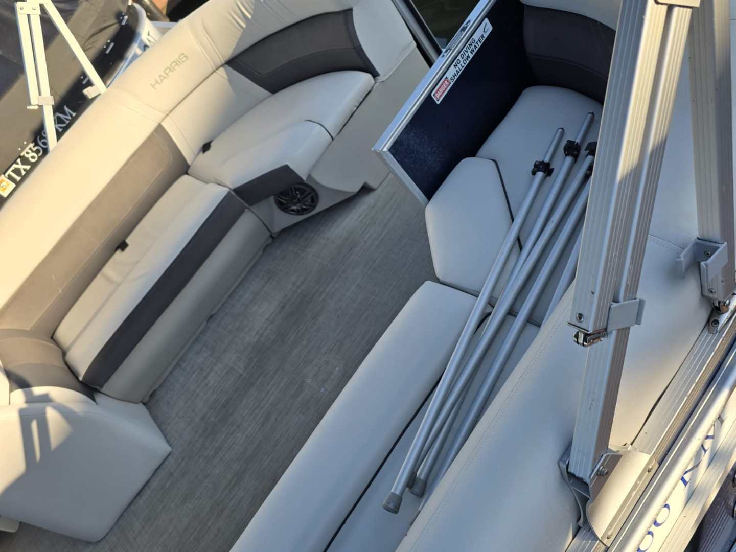 Empty pontoon boat with gray seating and metal railings.