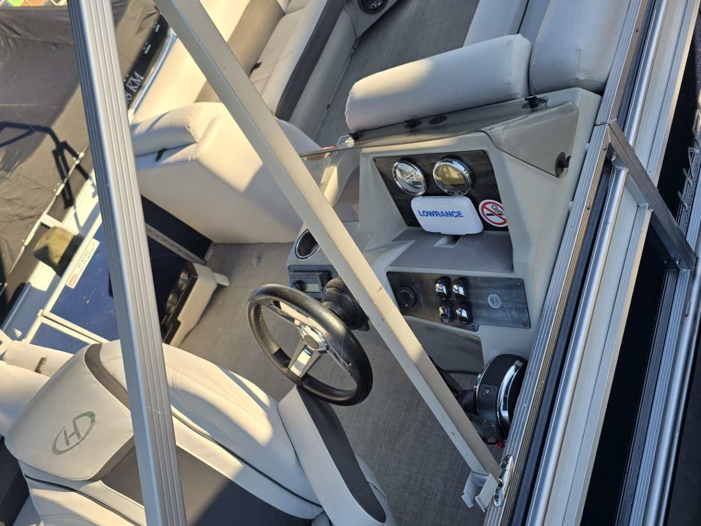 Interior of a boat with modern seats, steering wheel, and control panel.