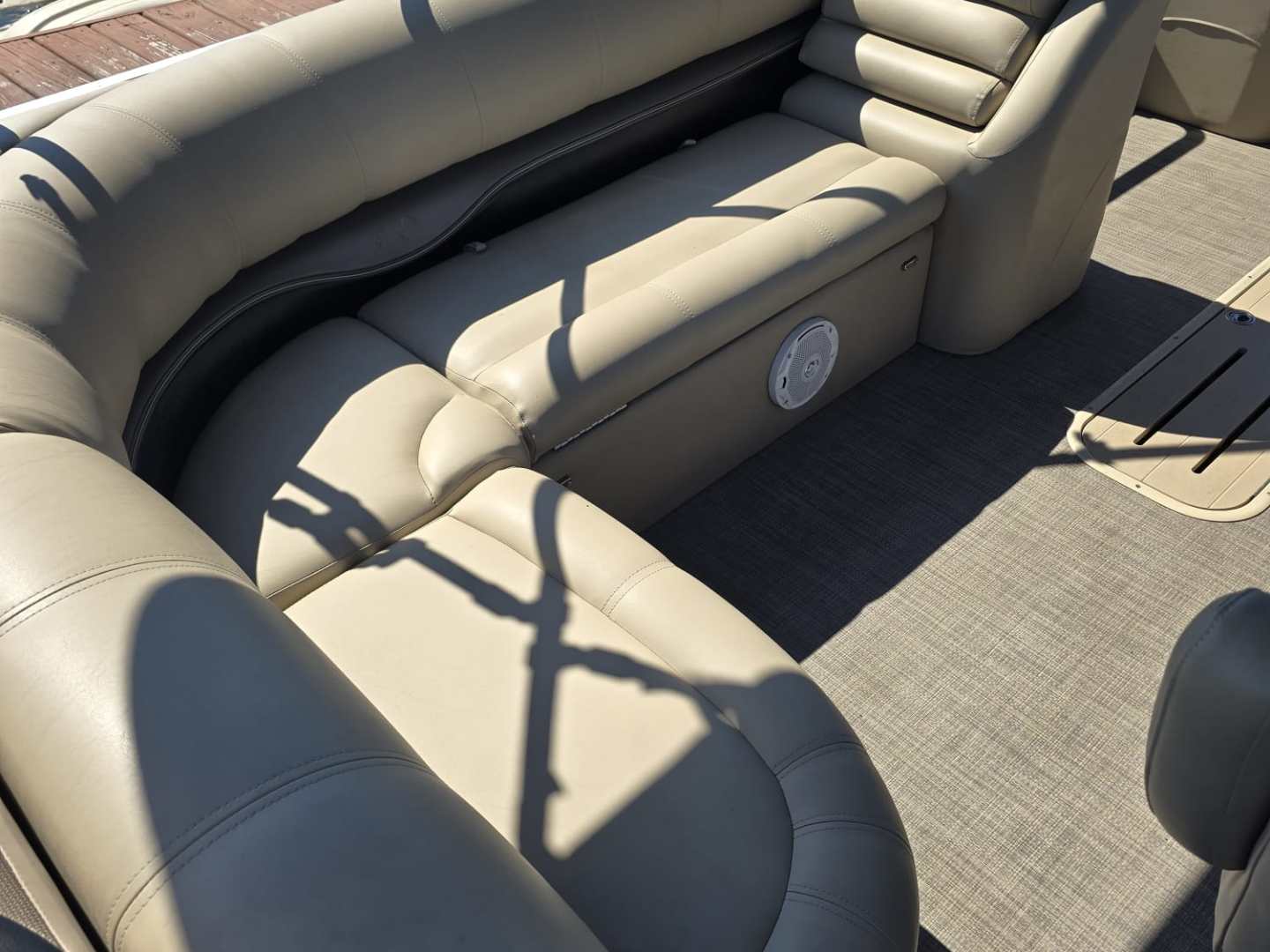 Empty beige leather boat seating under sunlight, with people visible in background.