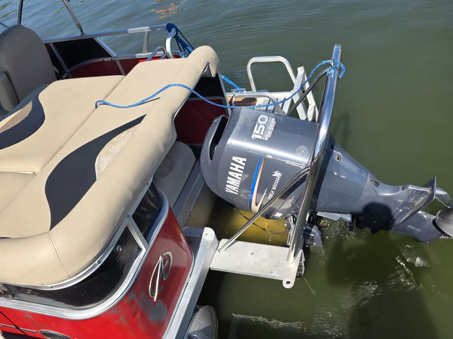 Red and beige pontoon boat with Yamaha motor on calm water.
