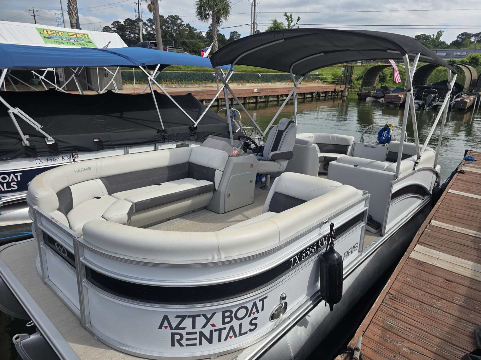 Pontoon boat docked, with 'Azty Boat Rentals' displayed on the side.