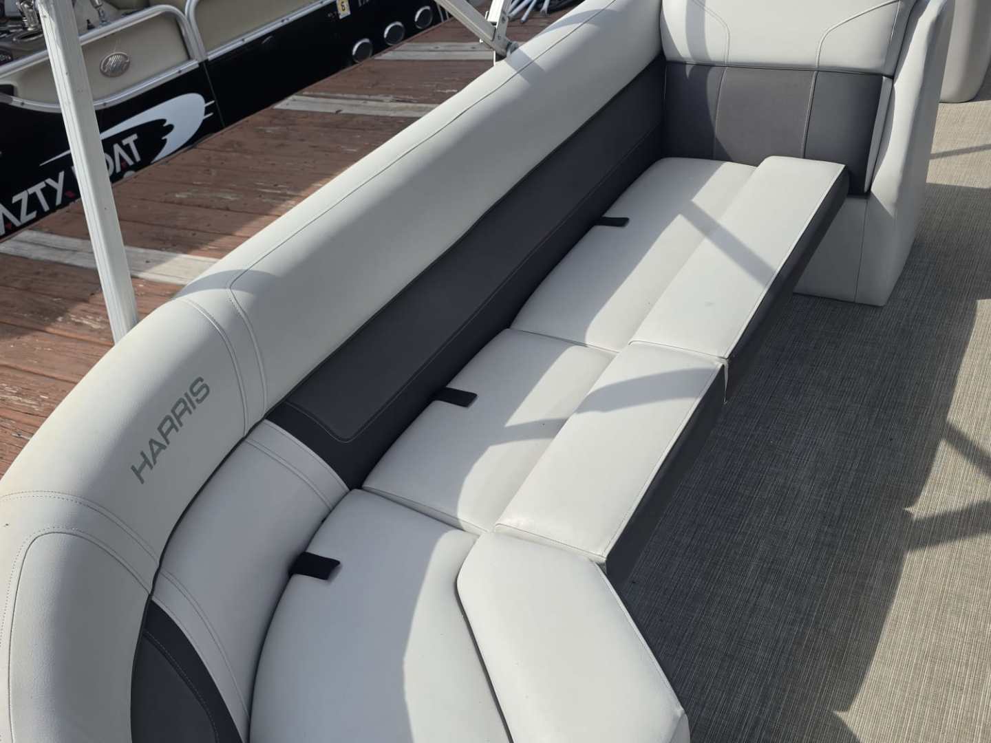 Gray curved boat seating on a dock with boats in the background.