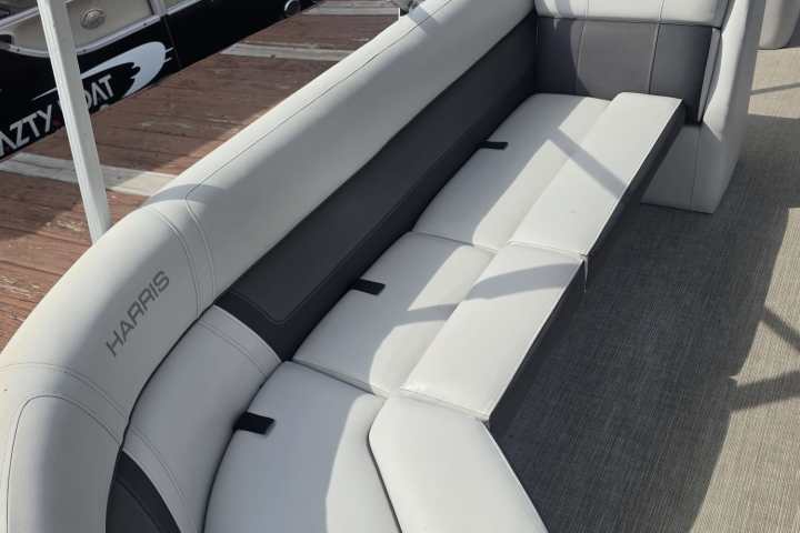 Gray curved boat seating on a dock with boats in the background.