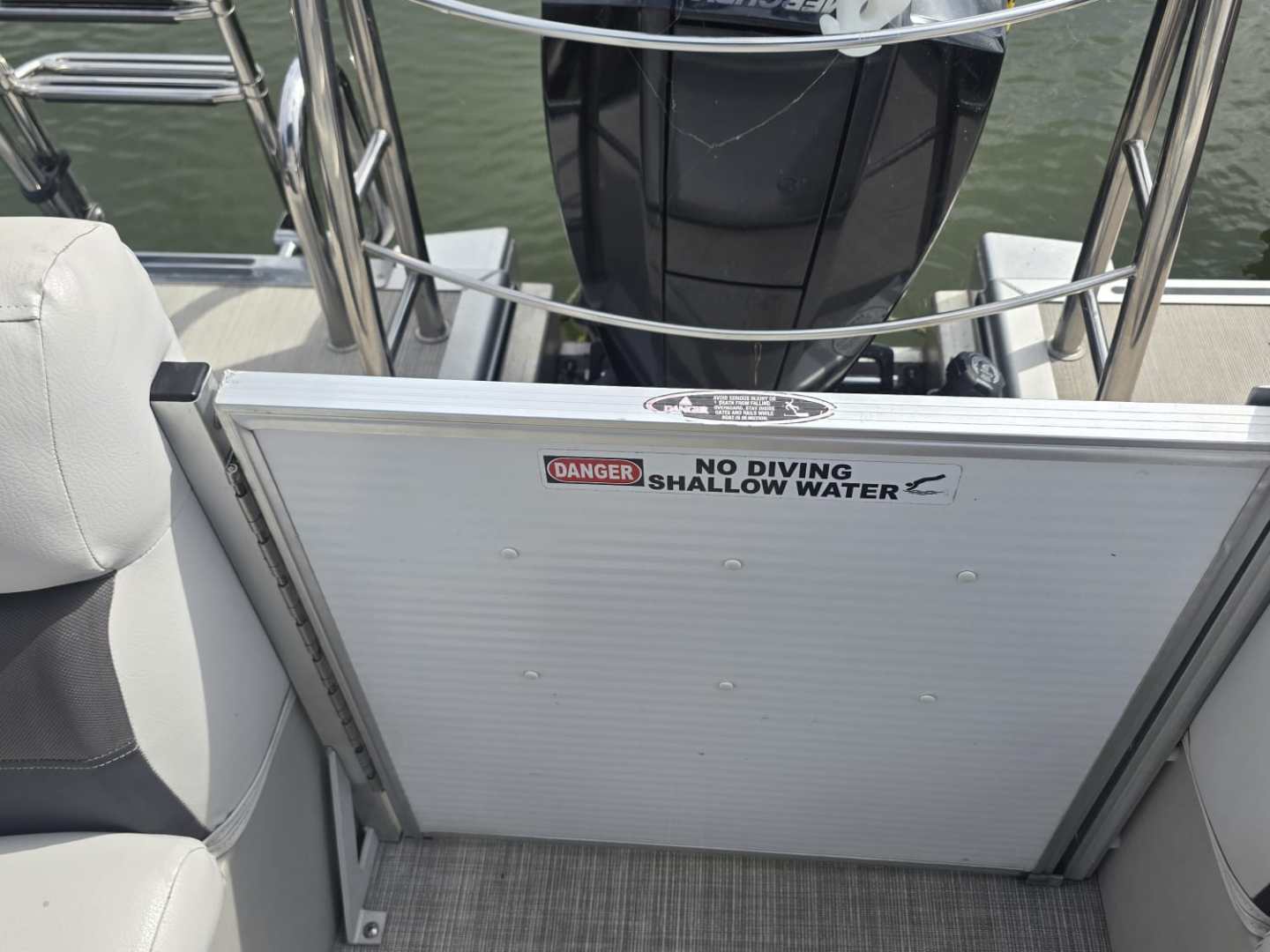 Boat with outboard motor, rope, and 'No Diving' sign on the deck.