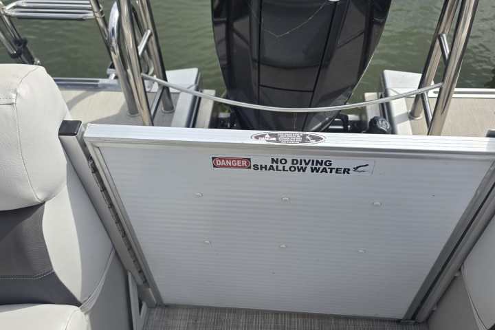 Boat with outboard motor, rope, and 'No Diving' sign on the deck.