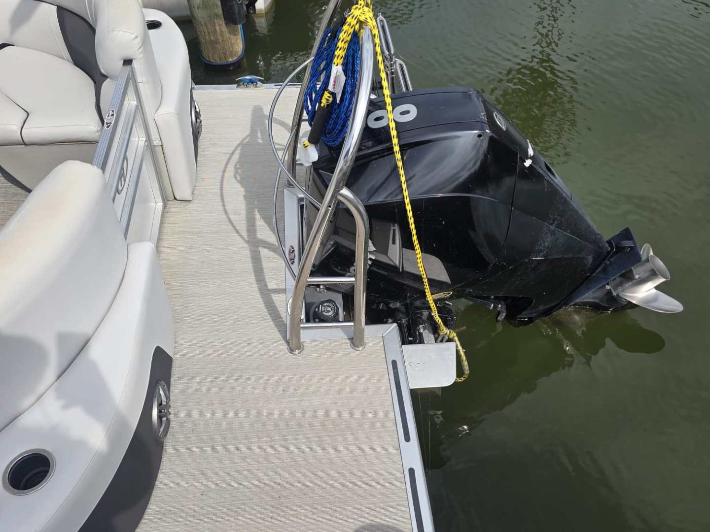 Pontoon boat with outboard motor docked on water.